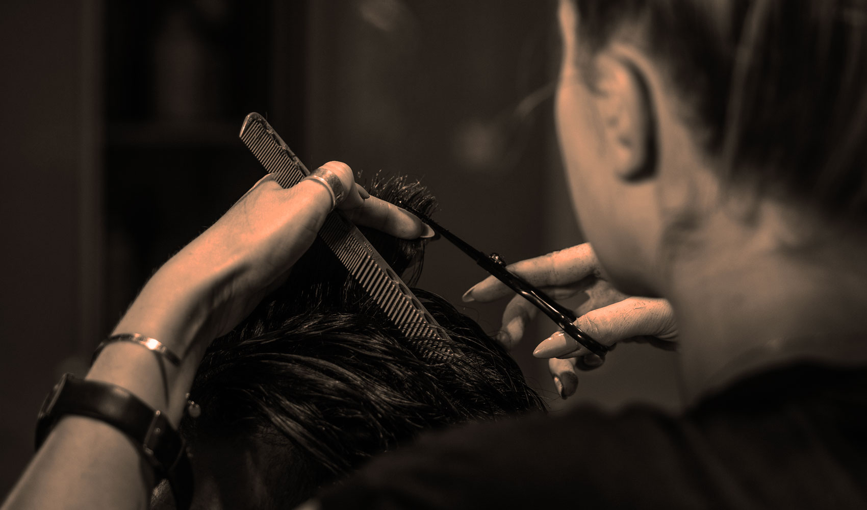 Coiffeuse du salon de coiffure Didier Commincas coupant les cheveux d'un homme